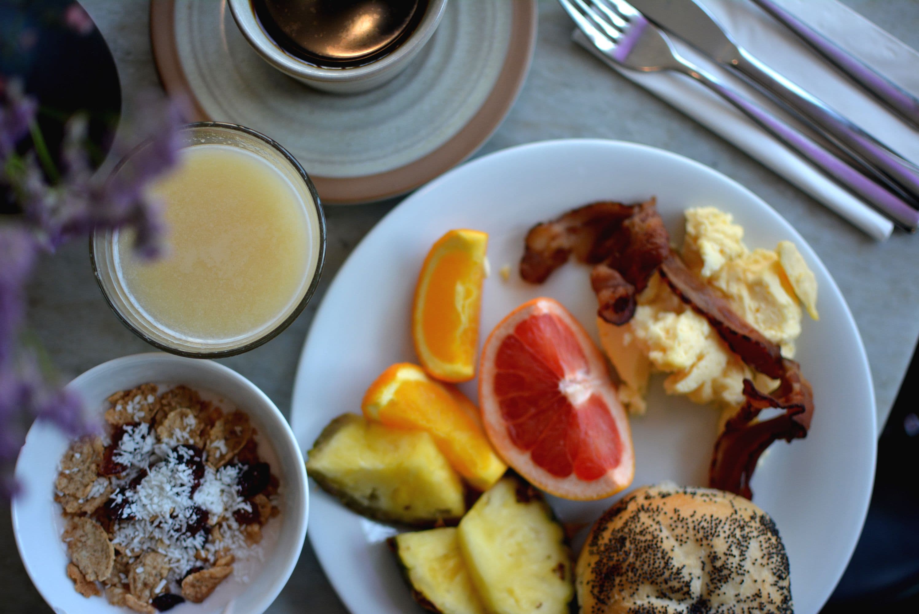 Un piatto per la colazione con uova, pancetta, arancia, pompelmo e cereali.
