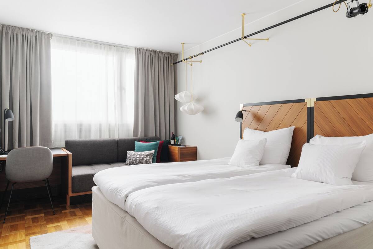 Quarto de hotel moderno com uma cama grande, uma escrivaninha e uma cadeira.