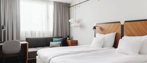 A modern hotel room with a large bed, a desk, and a chair.