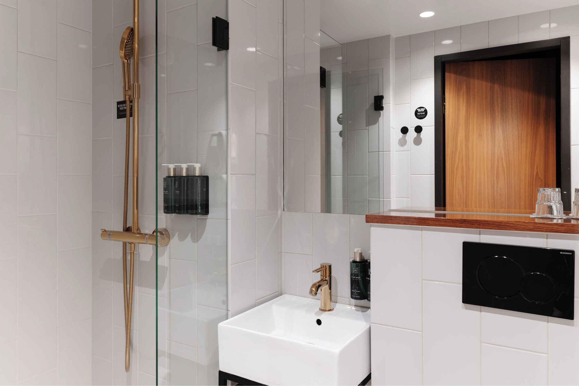 A modern bathroom with a glass-enclosed shower, a white sink, and a wooden vanity.