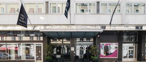 The Clarion Hotel Amaranta entrance with a covered entrance, large windows, and two flags.