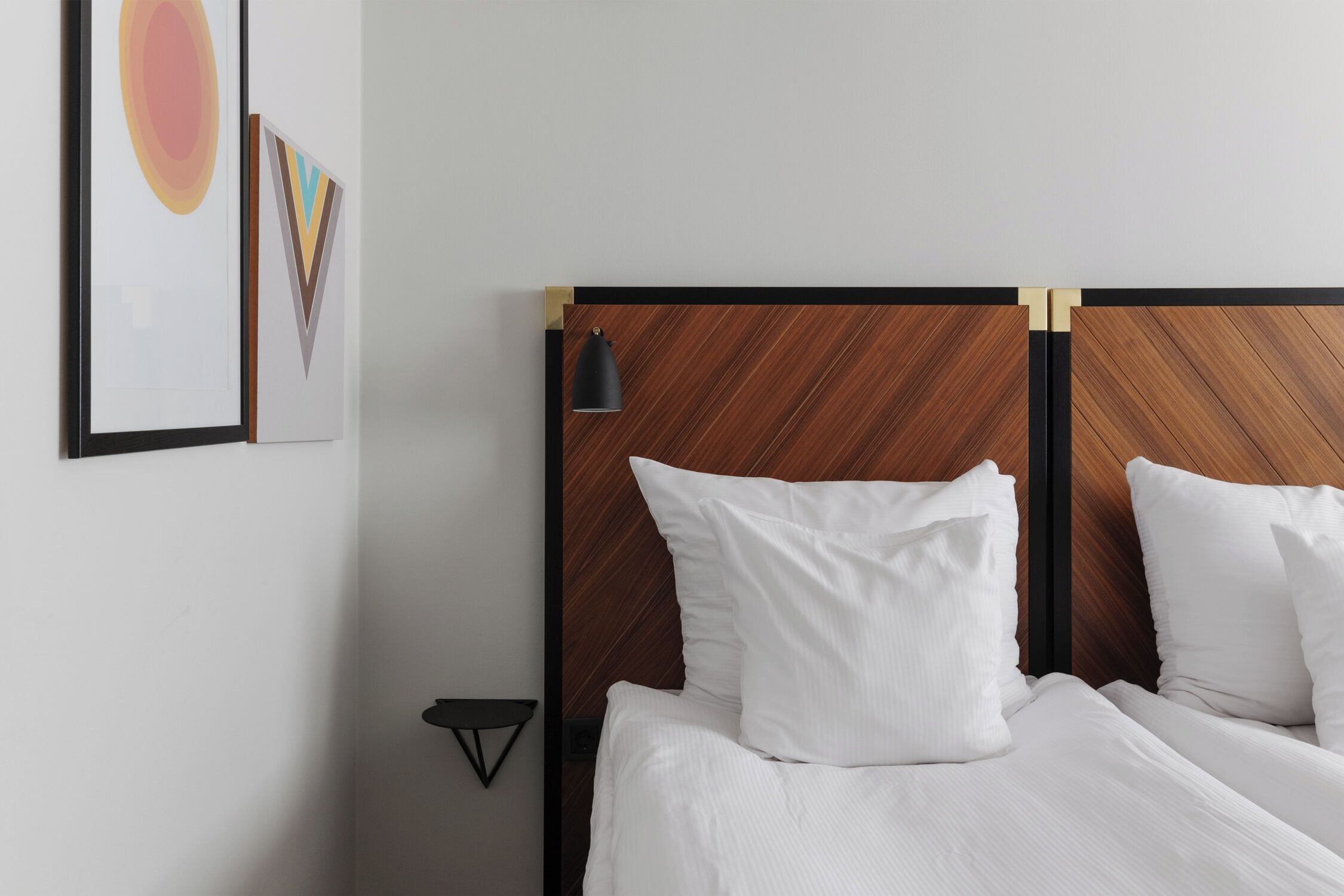 A neatly made bed with white linens, a wooden headboard, and a small bedside table with a lamp.