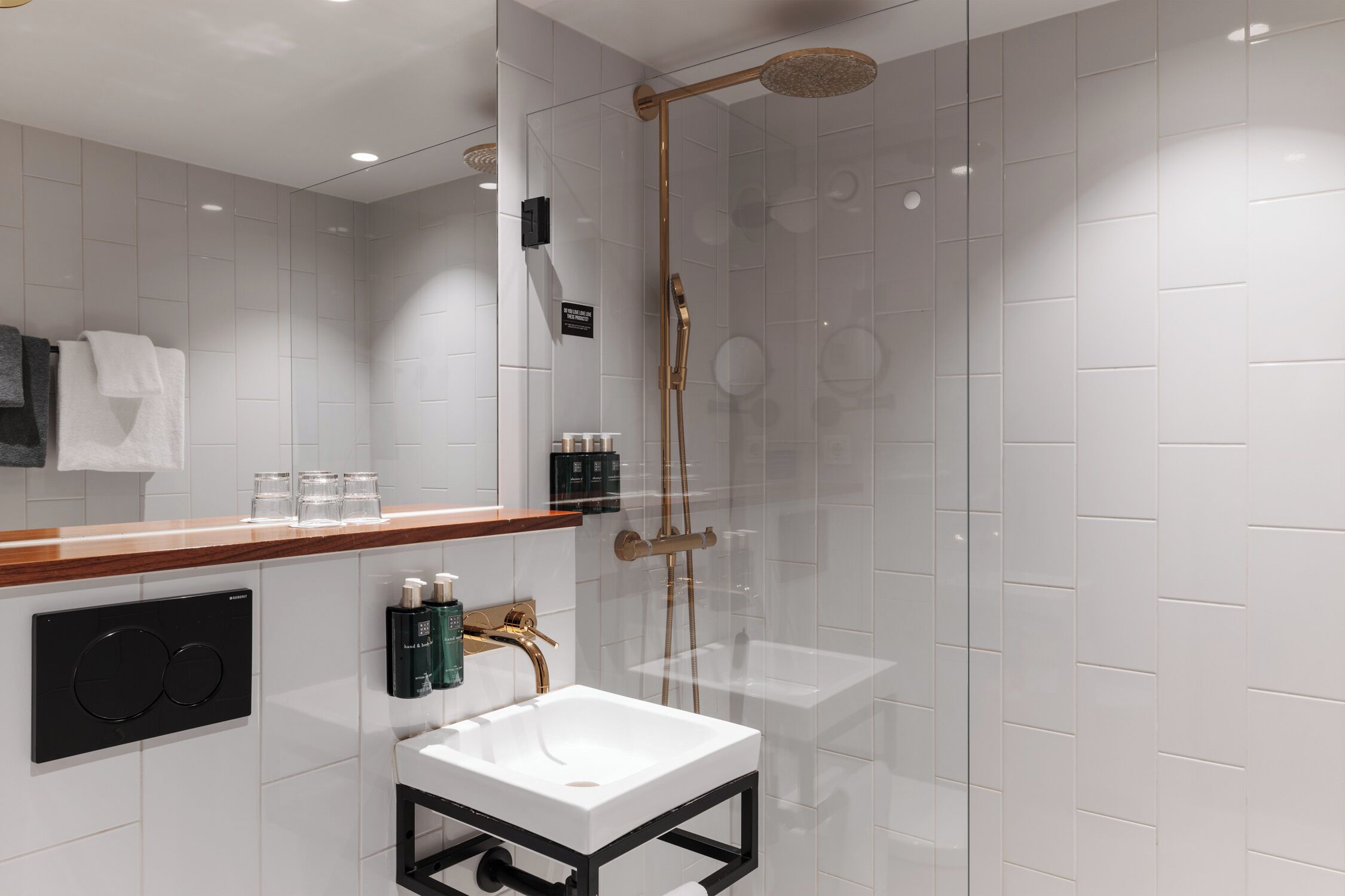 A modern bathroom with a glass-enclosed shower, a white sink, and a wooden countertop.