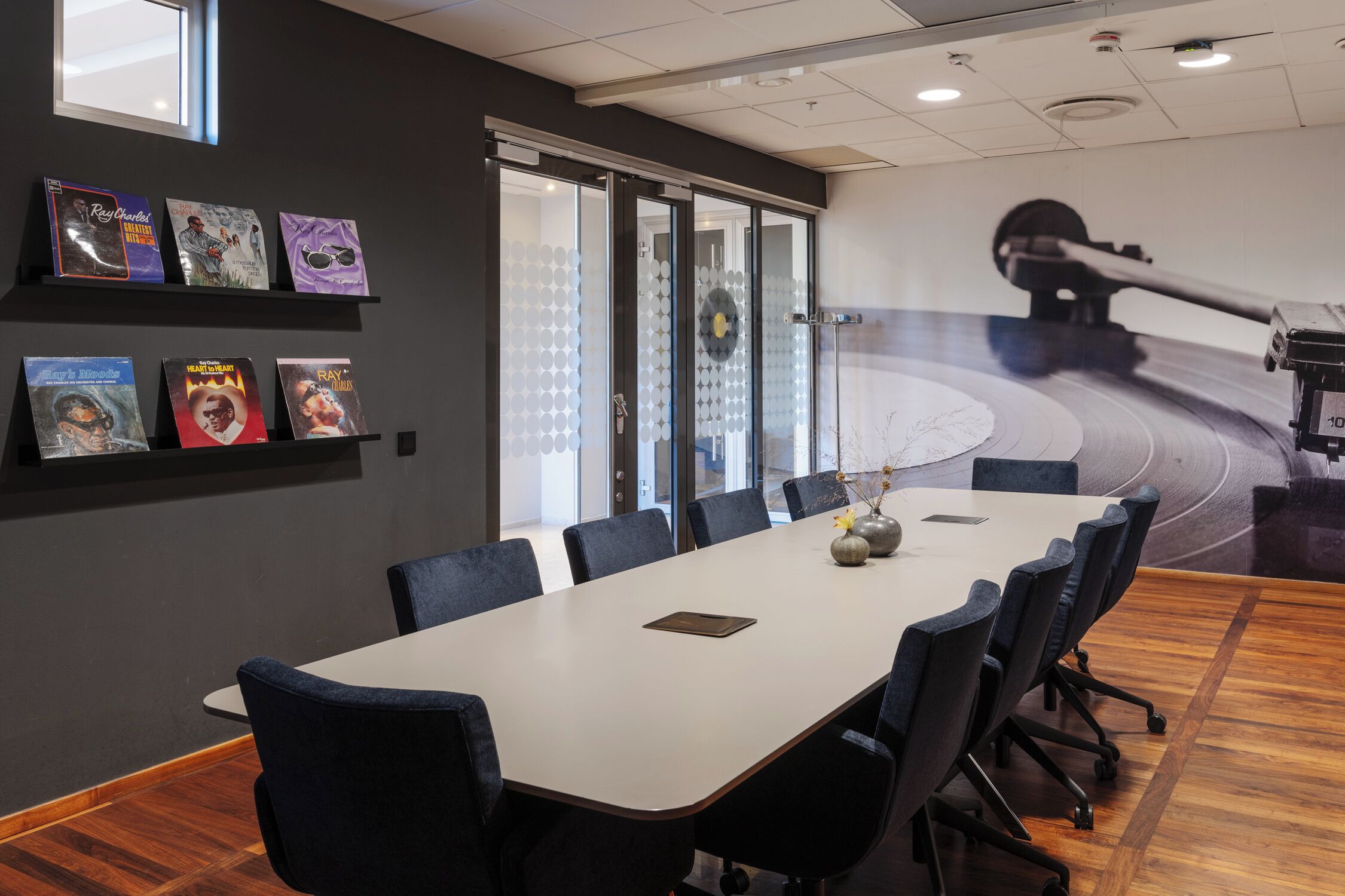 A conference room with a long table, chairs, and a glass wall with frosted panels.