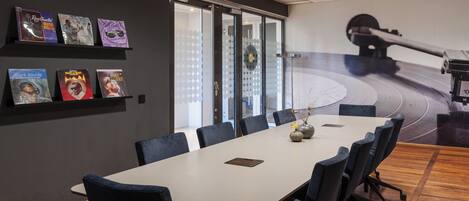 A conference room with a long table, chairs, and a glass wall with frosted panels.
