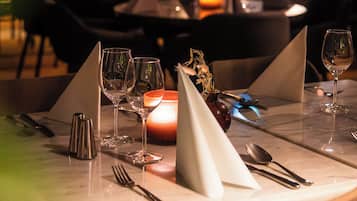 A restaurant setting with tables set for dining, featuring candles and glassware.
