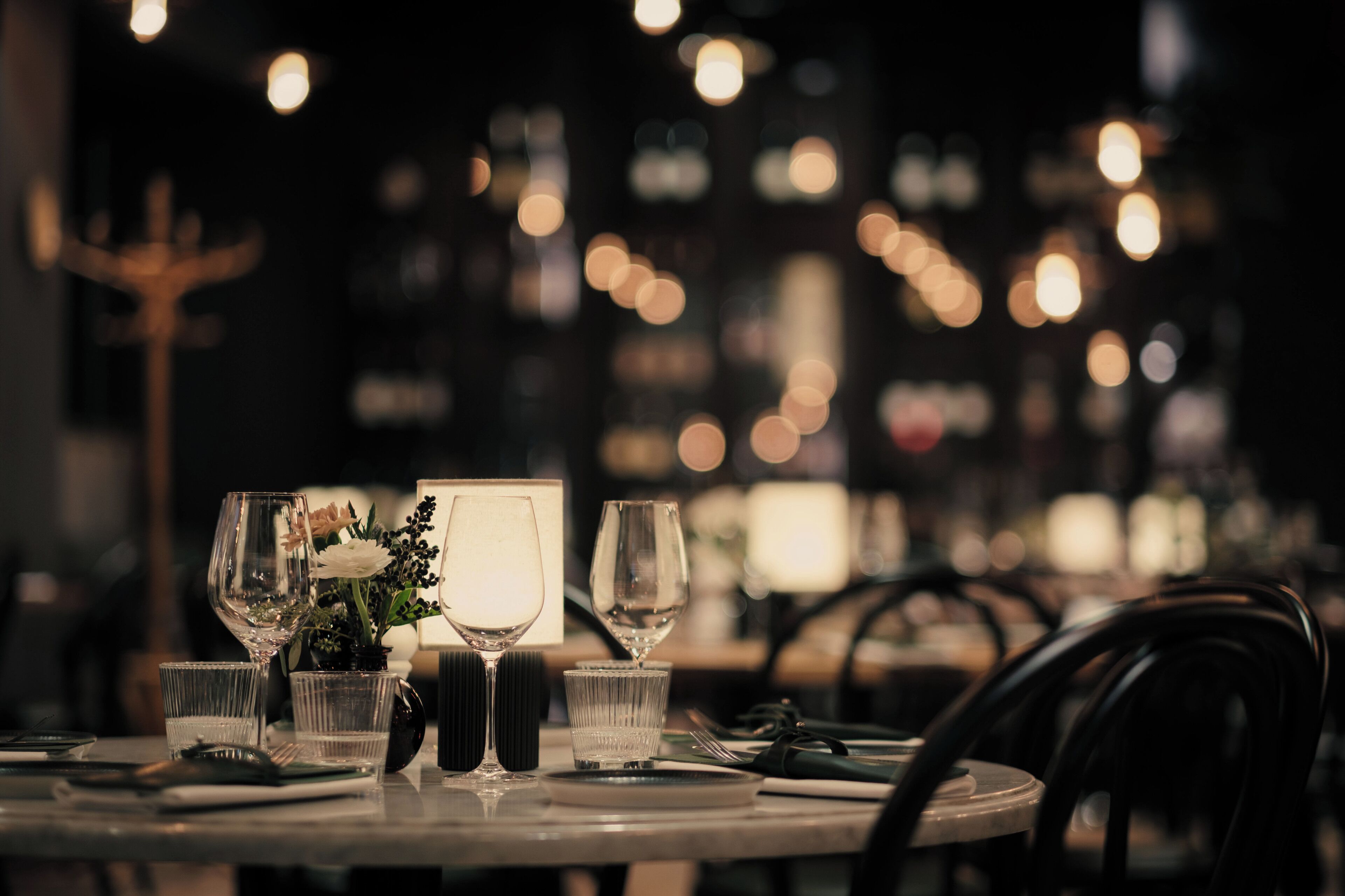 A dining table set with wine glasses, a candle, and a vase with flowers.