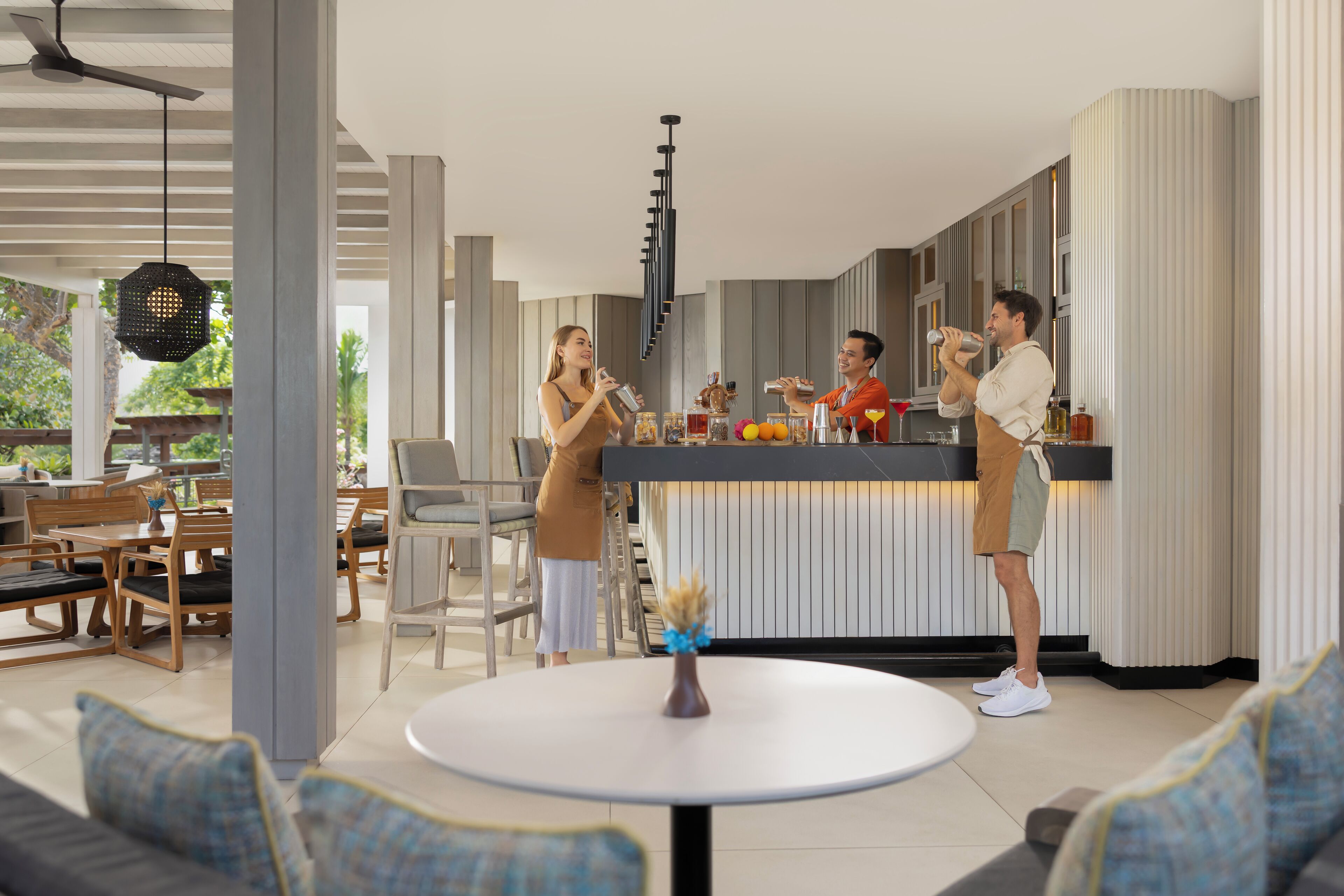 Een moderne keuken met een centraal eiland, houten meubels en een zithoek met een ronde tafel en banken.