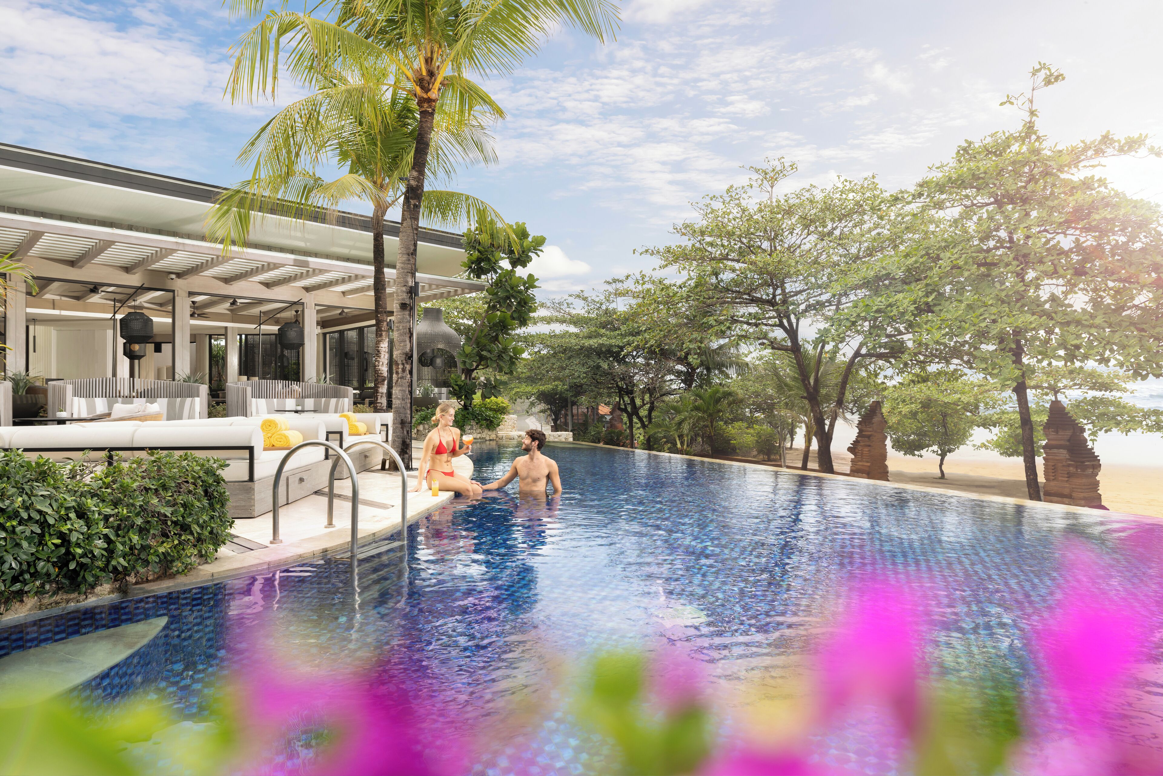 A swimming pool with a modern poolside area, including a covered seating area and a palm tree.