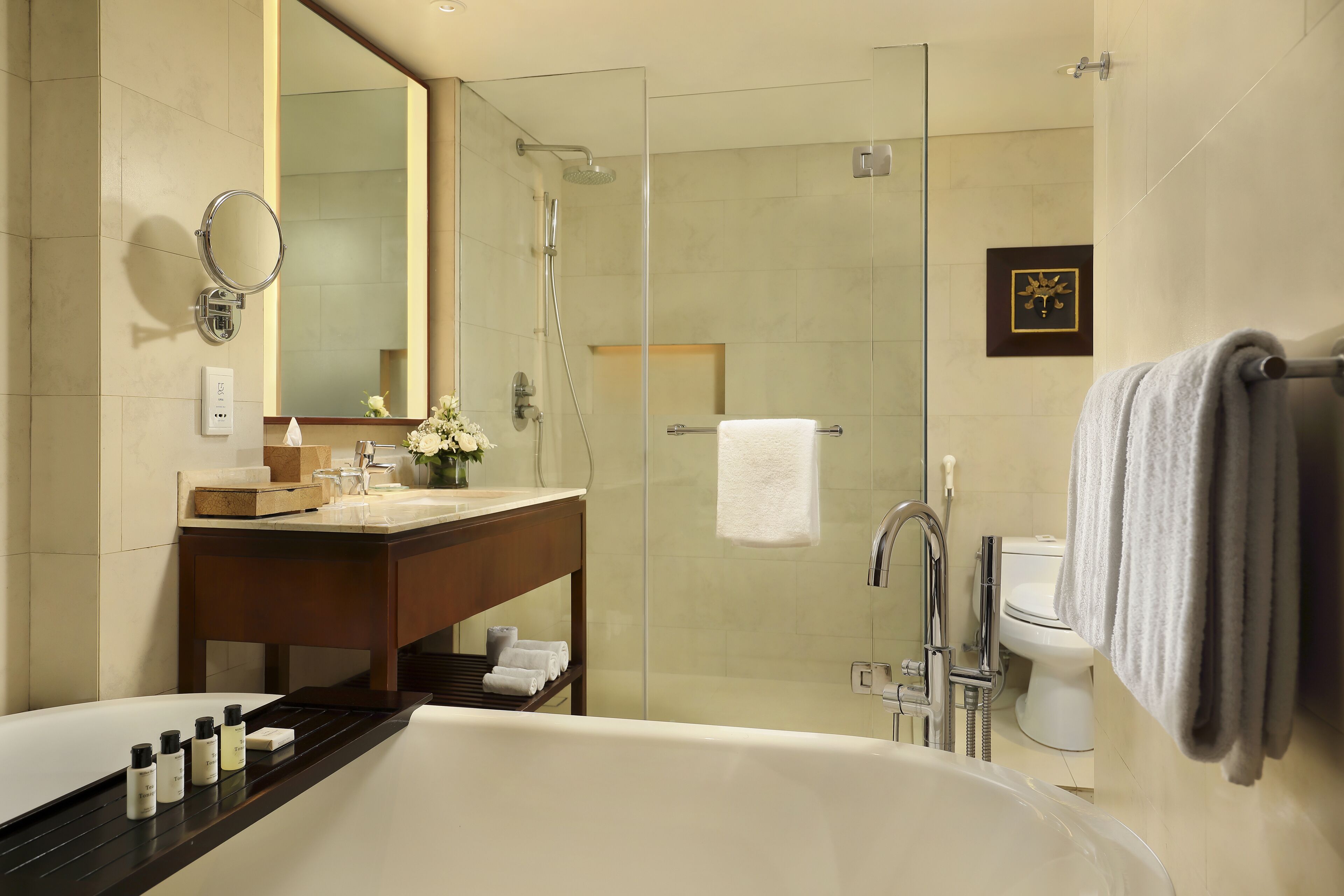 A modern bathroom with a large bathtub, a glass-enclosed shower, a vanity with a mirror, and a toilet.