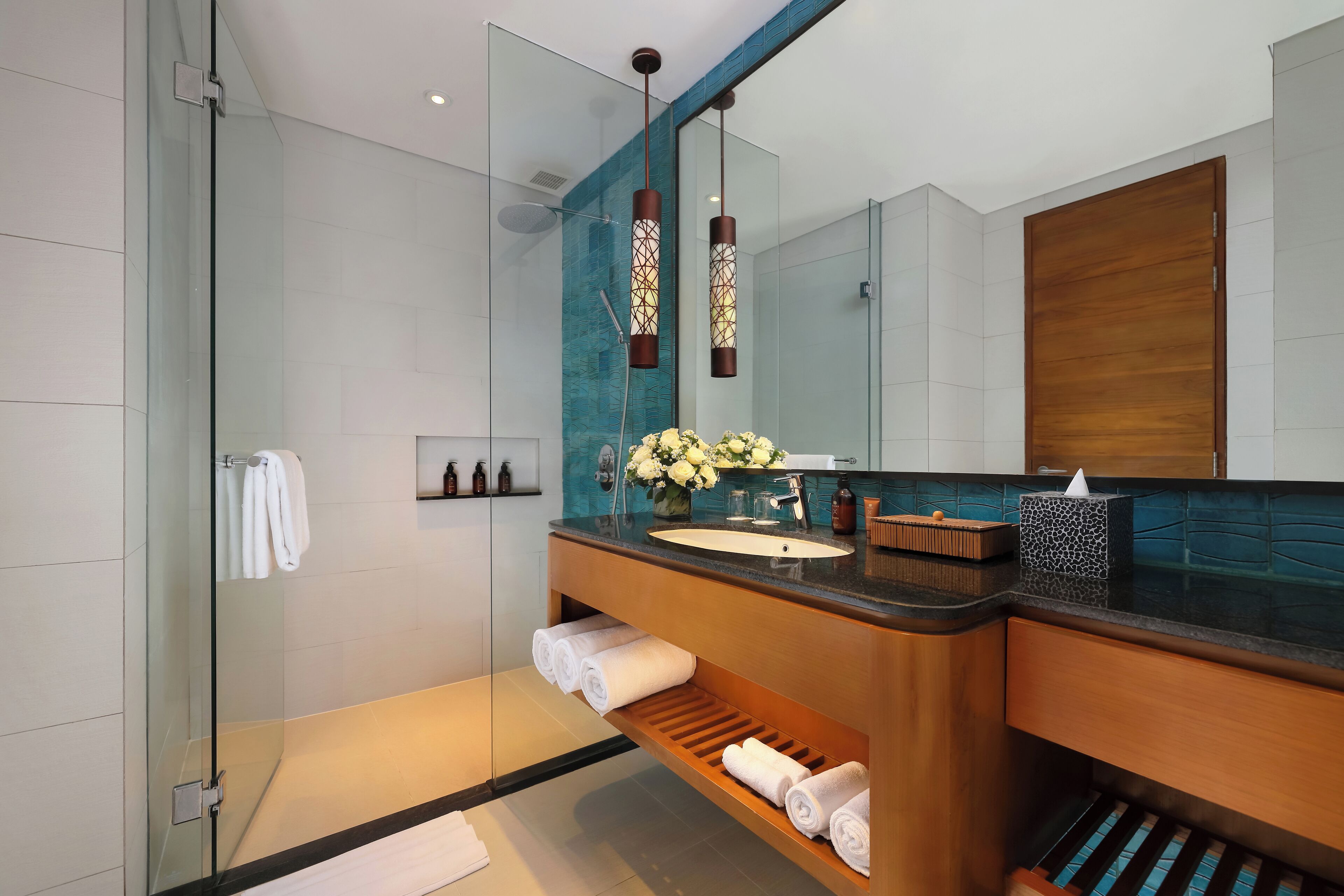 A modern bathroom with a glass shower enclosure, a wooden vanity with a sink, and a large mirror.
