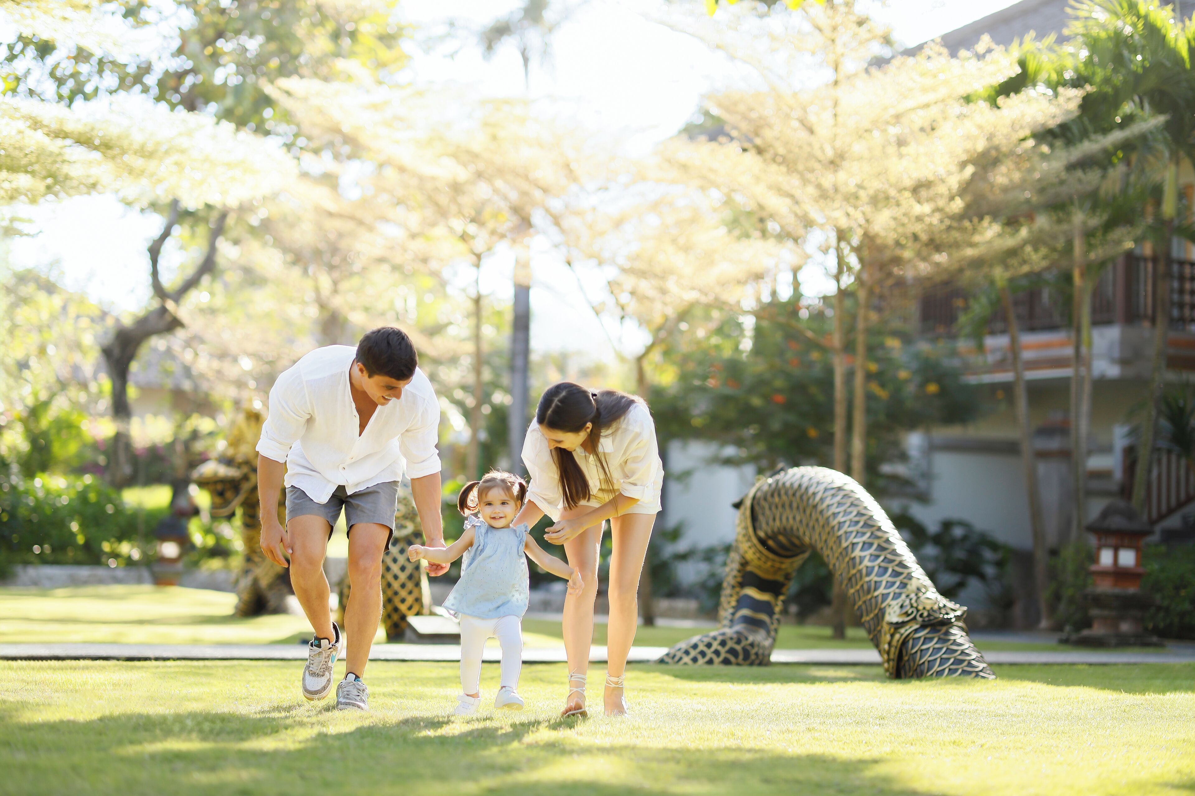 A family walking in a park with a giraffe statue.