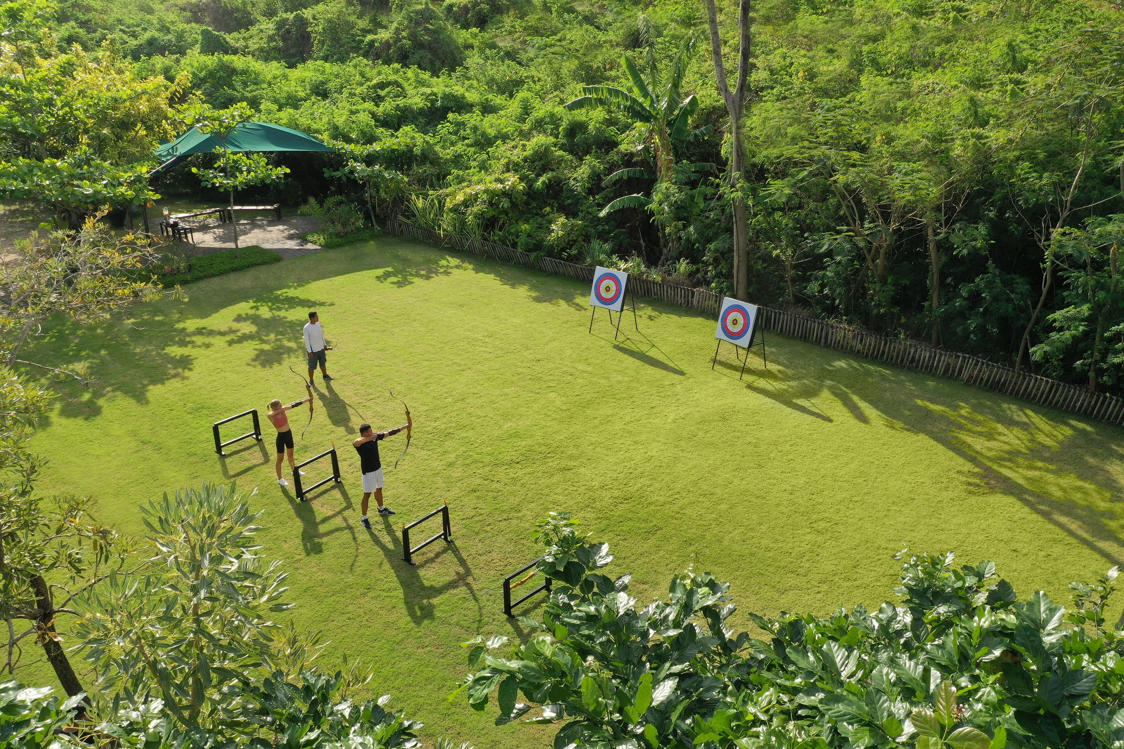 A well-maintained lawn with two archery targets and a person practicing archery.