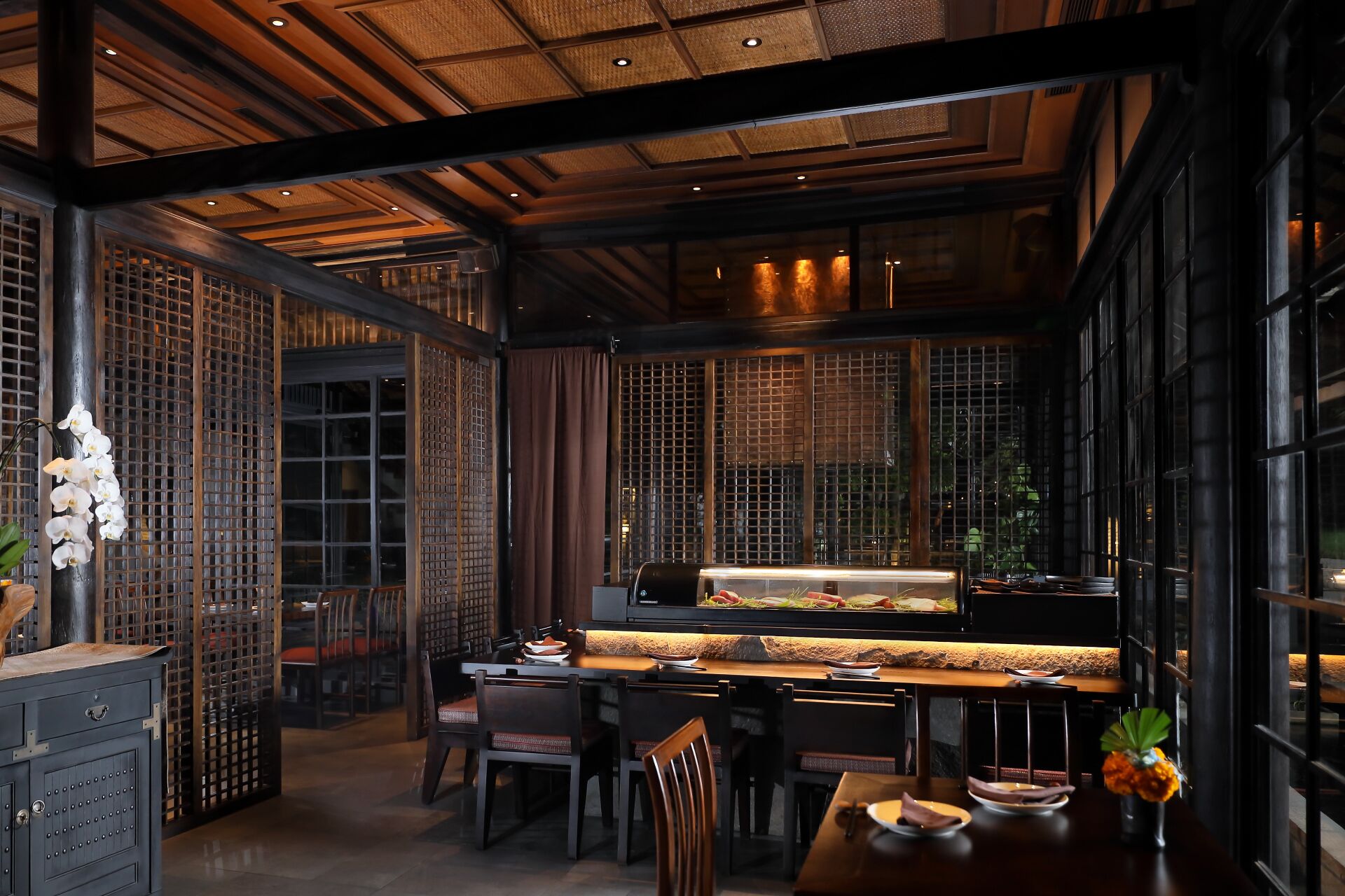 A restaurant interior with a sushi bar, wooden ceiling, and traditional decor.