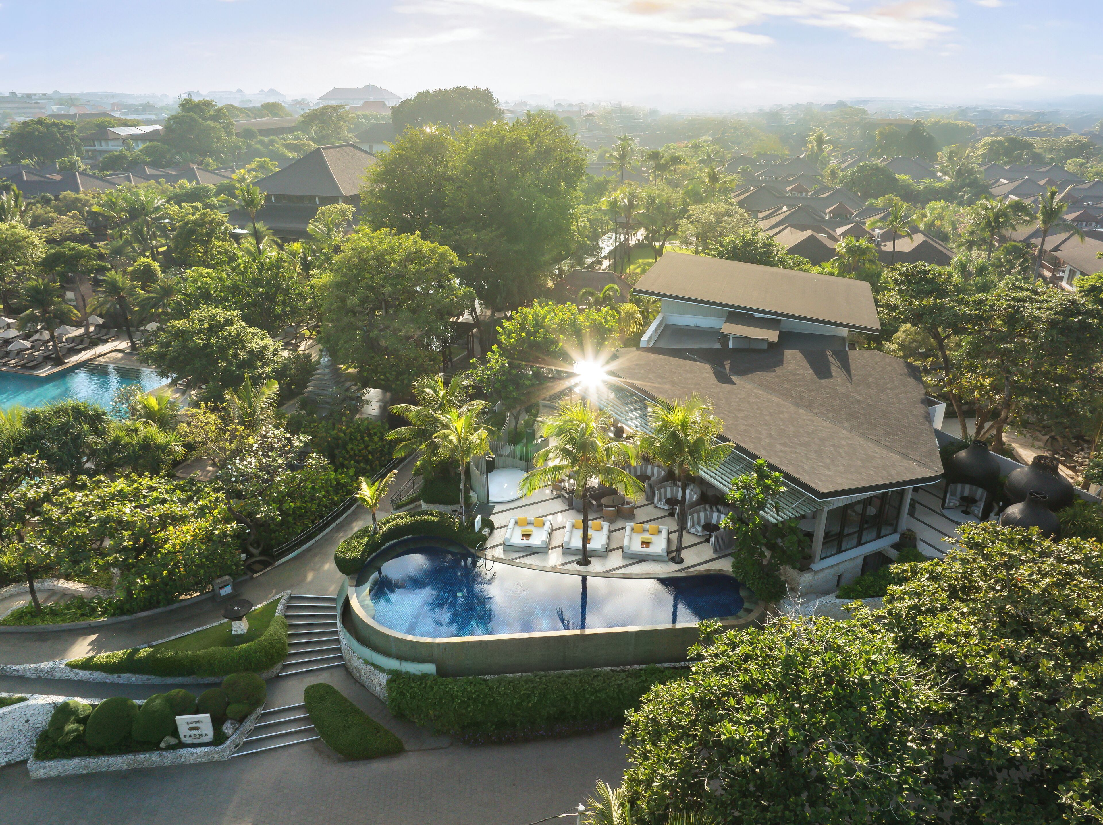 A resort with a swimming pool, palm trees, and a view of the surrounding area.