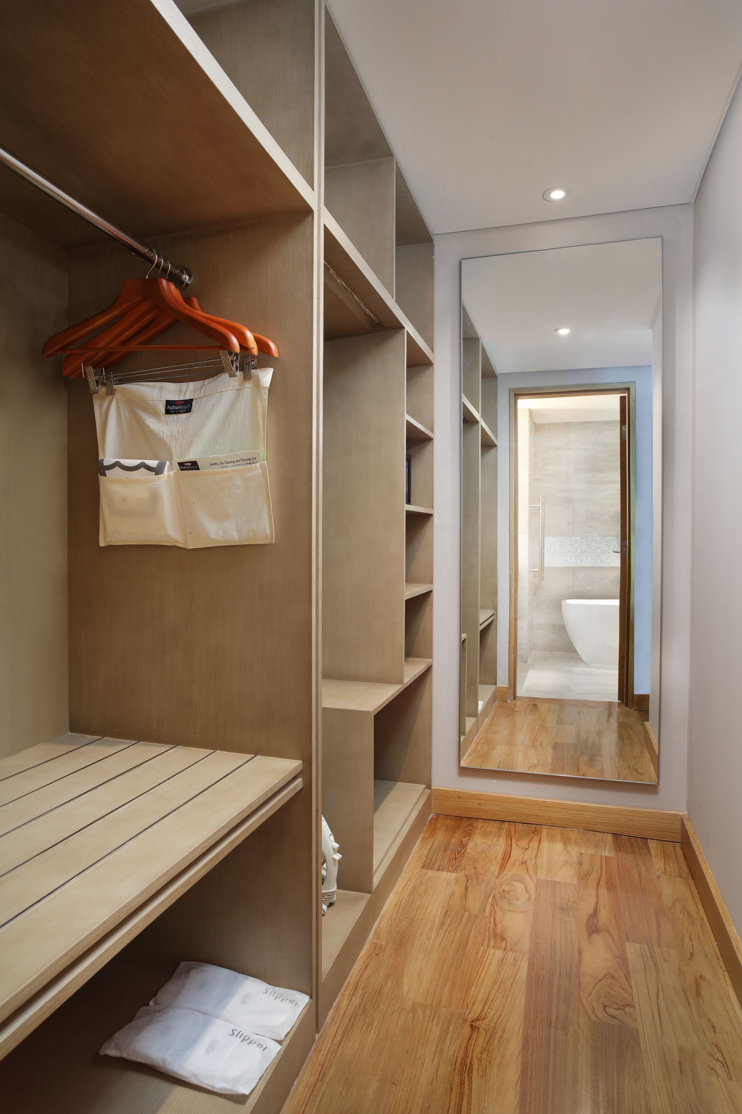 Ein modernes Badezimmer mit großem Spiegel, Holzboden und bodengleicher Dusche.