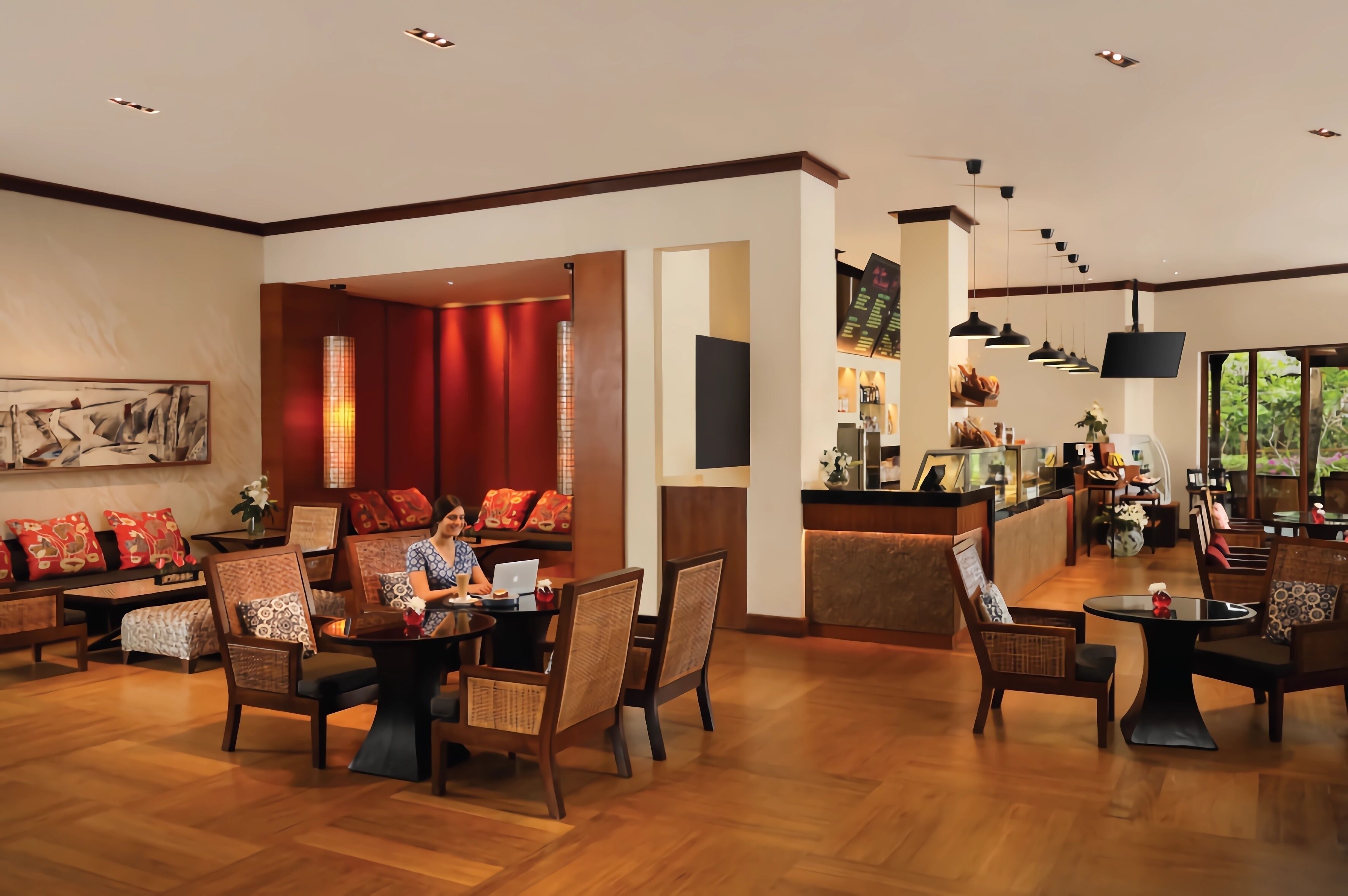 A spacious lobby with wooden flooring, comfortable seating areas, a reception desk, and a bar.