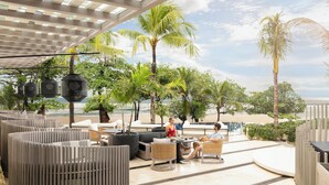 An outdoor seating area with a view of the beach, featuring modern furniture and potted plants. - Padma Resort Legian (Legian)