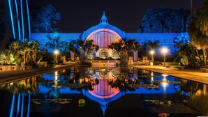 A nighttime view of a building with a large dome and arched windows, surrounded by palm trees and a reflecting pool. - Pier South Resort, Autograph Collection by Marriott (Imperial Beach)