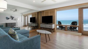 A modern living room with a large TV, comfortable seating, and a view of the ocean. - Pier South Resort, Autograph Collection by Marriott (Imperial Beach)