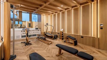 A gym with wooden floors, exercise equipment, and benches.
