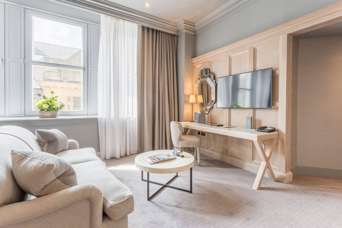 A modern living room with a sofa, a round coffee table, a desk, and a TV.