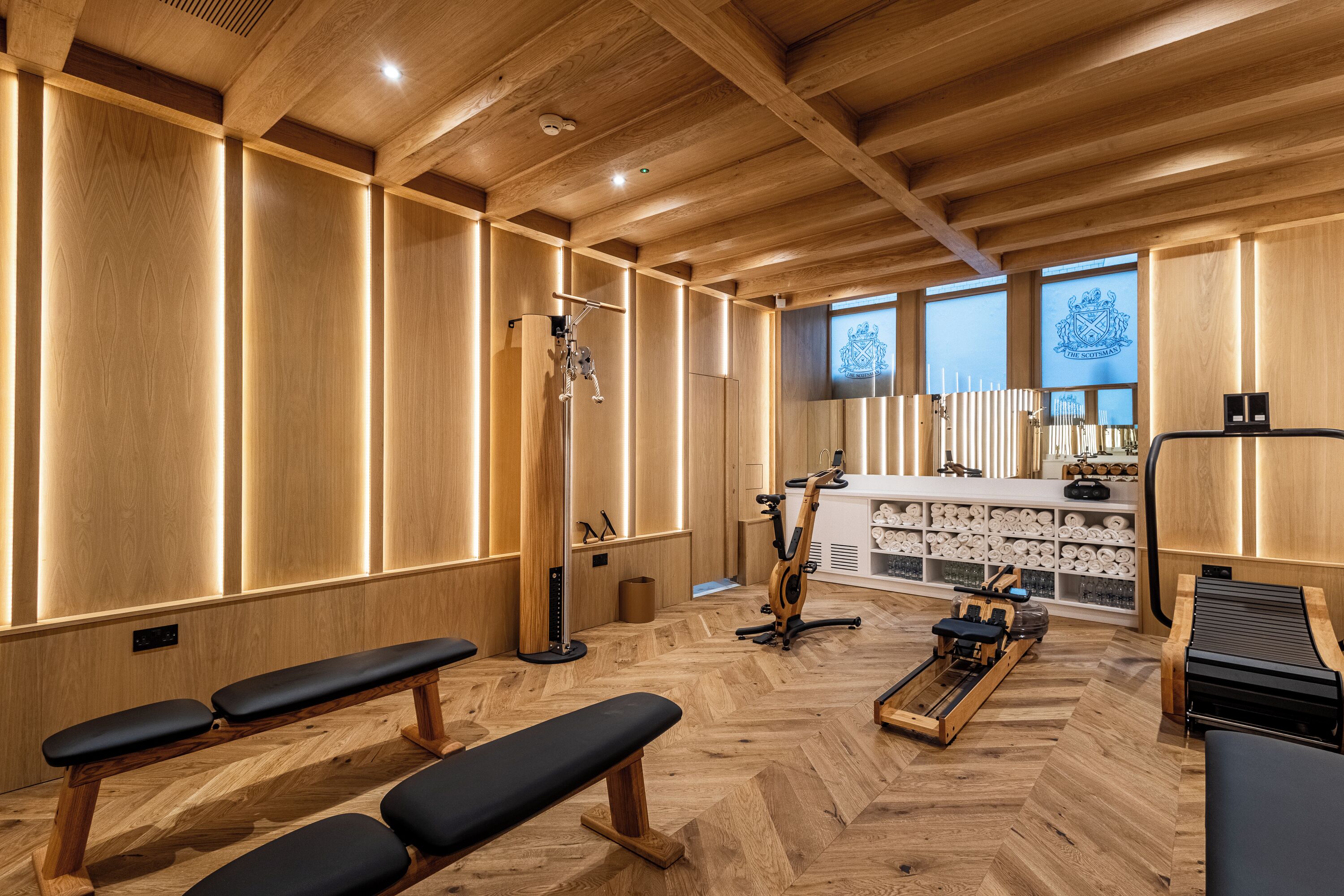 A wooden interior with benches, exercise equipment, and a counter with towels.