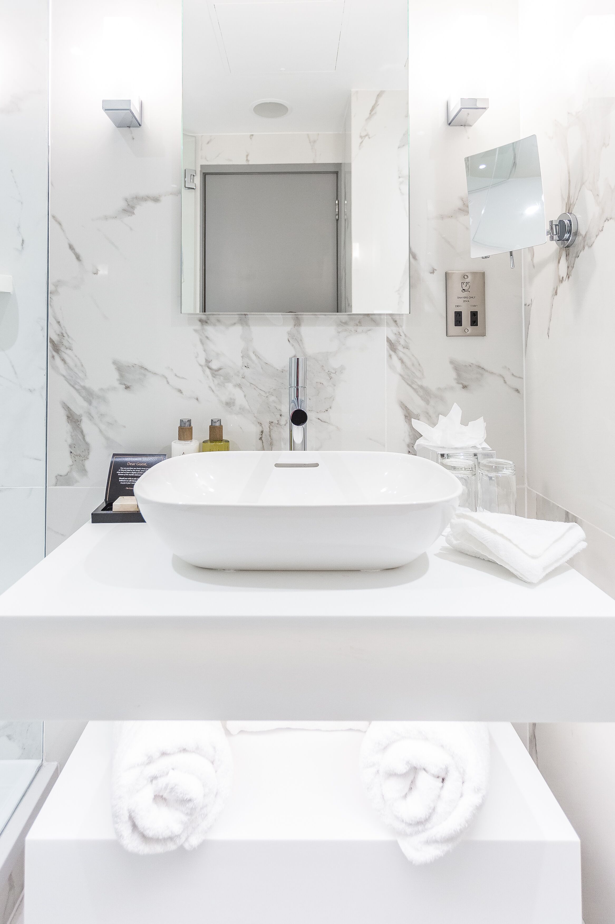 A modern bathroom with a large oval sink, a mirror, and a towel rack.