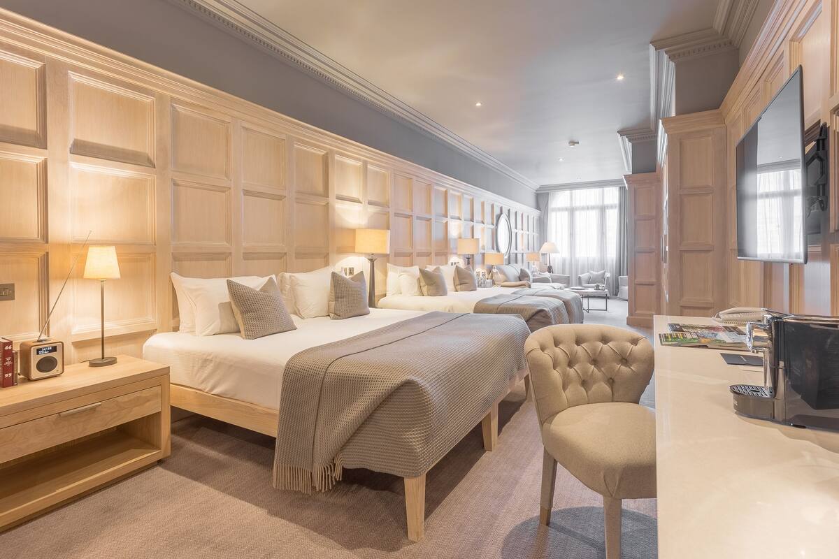 A hotel room with a large bed, bedside tables, a TV, and a seating area.