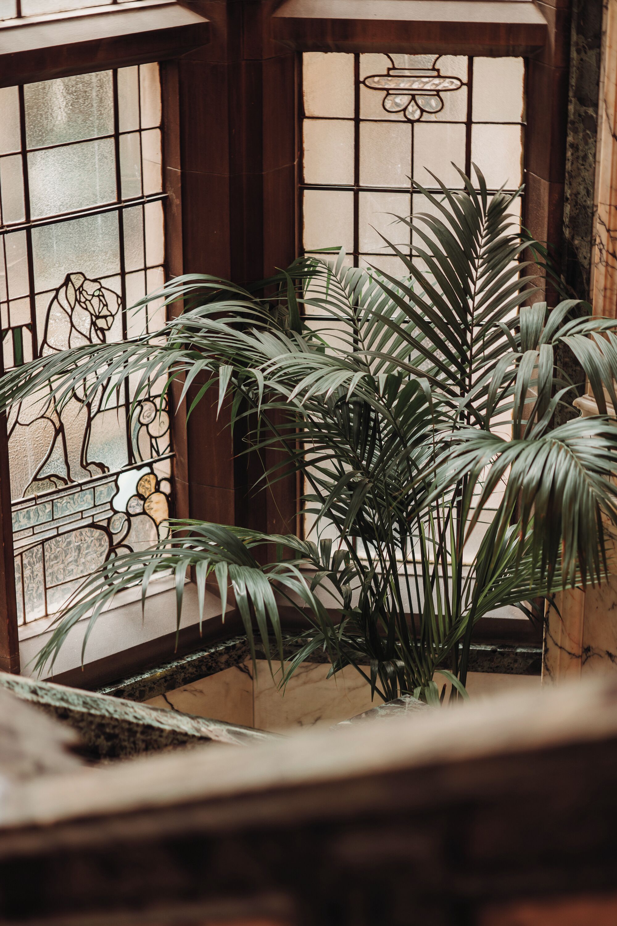 A room with a large window featuring stained glass and a view of a balcony with potted plants.