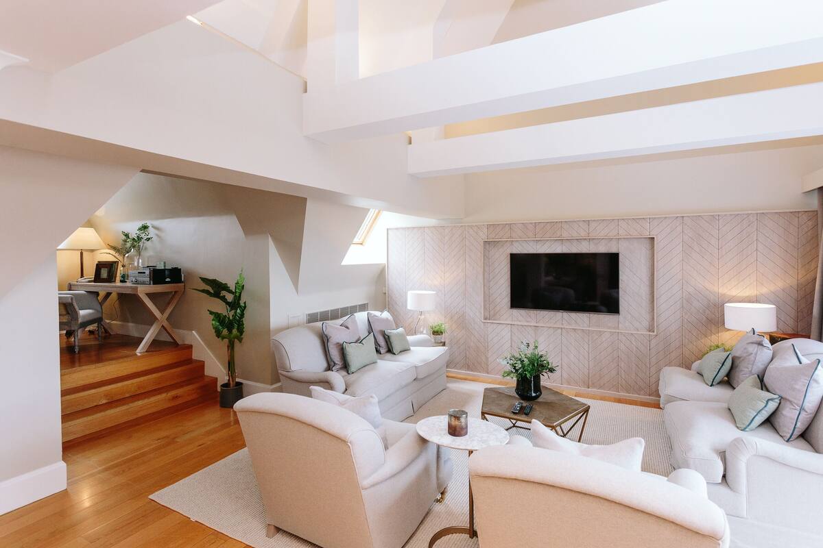 A modern living room with a sofa set, a coffee table, and a TV mounted on the wall.