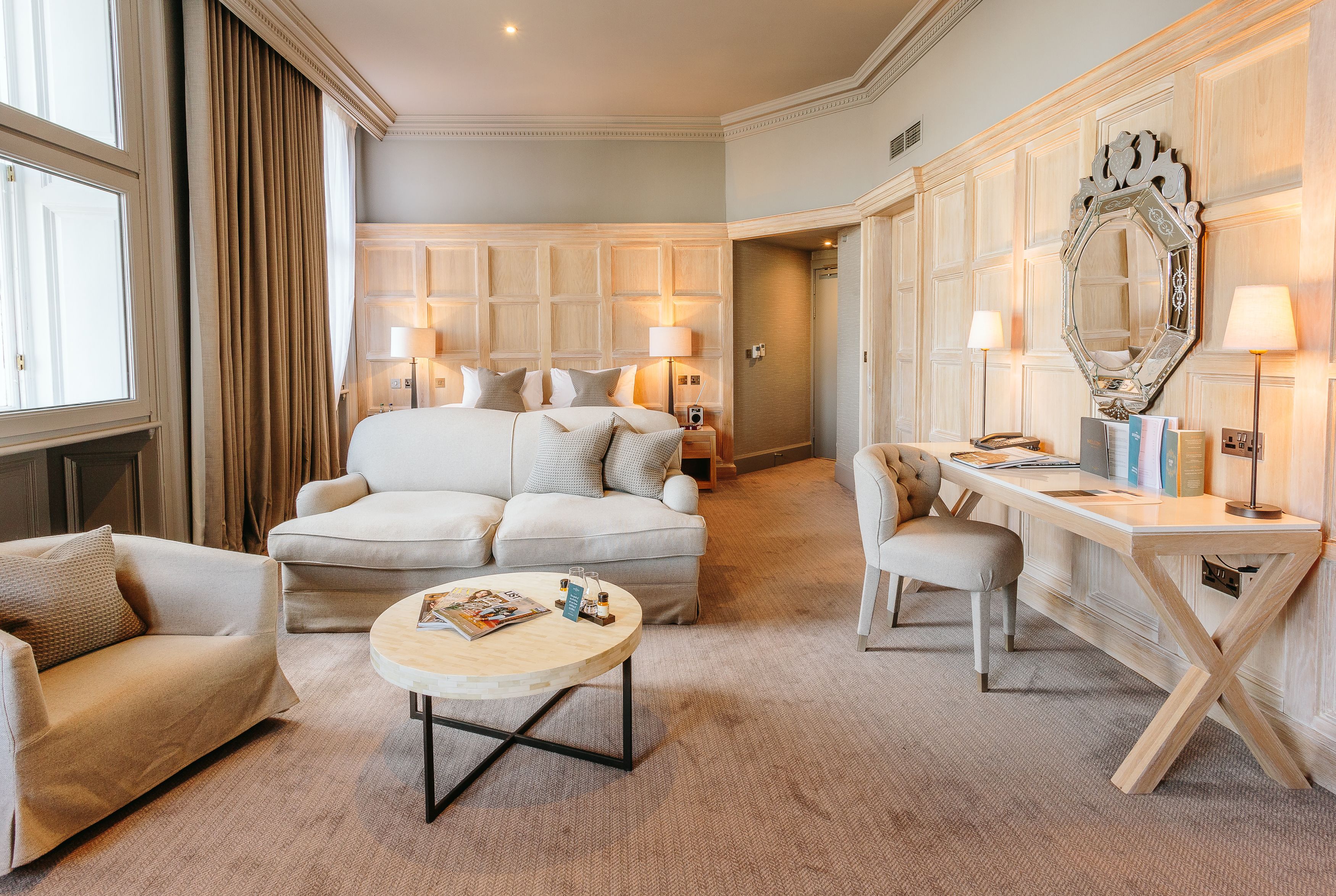 Een hotelkamer met een groot bed, twee slaapbanken, een kleine tafel en een bureau met een spiegel.