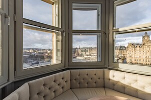 A corner seating area with a view of a cityscape through large windows.