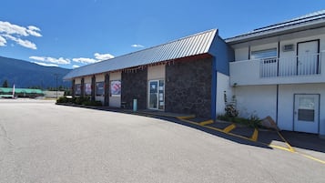 A two-story building with a stone facade and a metal roof, featuring a garage door and a balcony.
