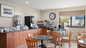 A modern kitchen and dining area with wooden cabinets, a coffee station, and a clock on the wall. - Super 8 by Wyndham Hagerstown I-70 (Hagerstown)
