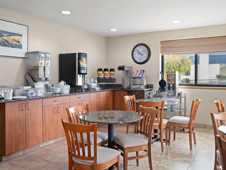Una cocina y comedor modernos con armarios de madera, un espacio para café y un reloj en la pared.