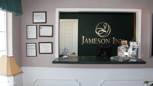 Una mesa de recepción con certificados enmarcados en la pared, un logo verde y material promocional.
