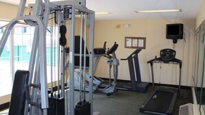 Un gimnasio con equipo de ejercicio, cintas de correr y un televisor montado en la pared.