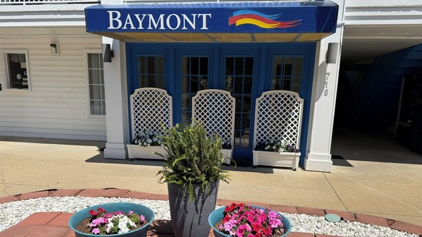 Een gebouw met een 'Baymont'-bordes, een blauwe deur en een bloembak met bloemen.