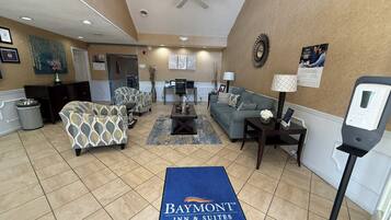A hotel lobby with seating areas, a reception desk, and a Baymont Inn & Suites sign.