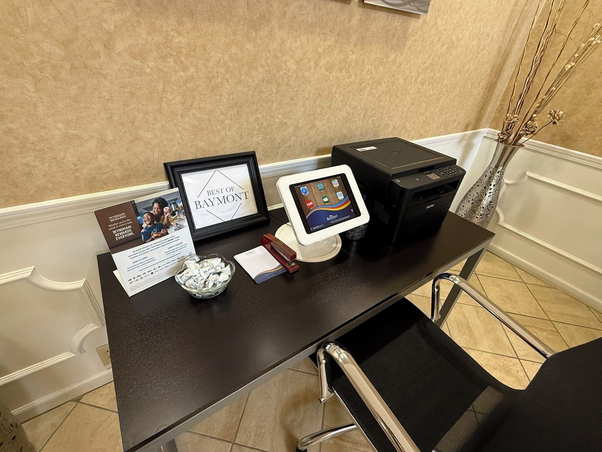 Un comptoir d’accueil avec un trophée encadré, une tablette, une imprimante et un bol rempli de pièces de monnaie.
