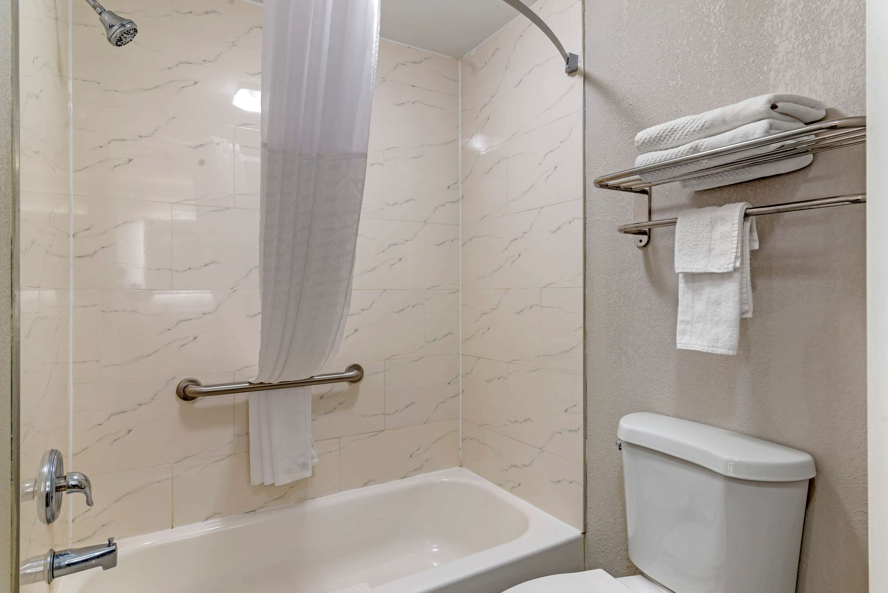 Un baño con bañera, ducha, inodoro y un perchero para toallas.