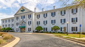 A large, white hotel with a central entrance, multiple windows, and a green awning.