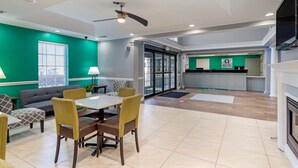 A spacious room with a dining area, a sofa, and a kitchen area with a counter and cabinets.