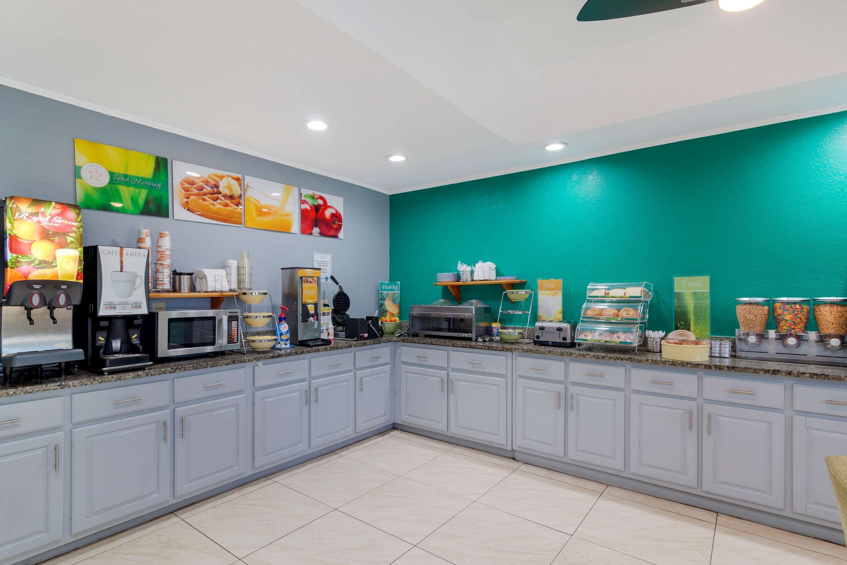 Un comedor con cafetera, microondas y varios recipientes de comida.