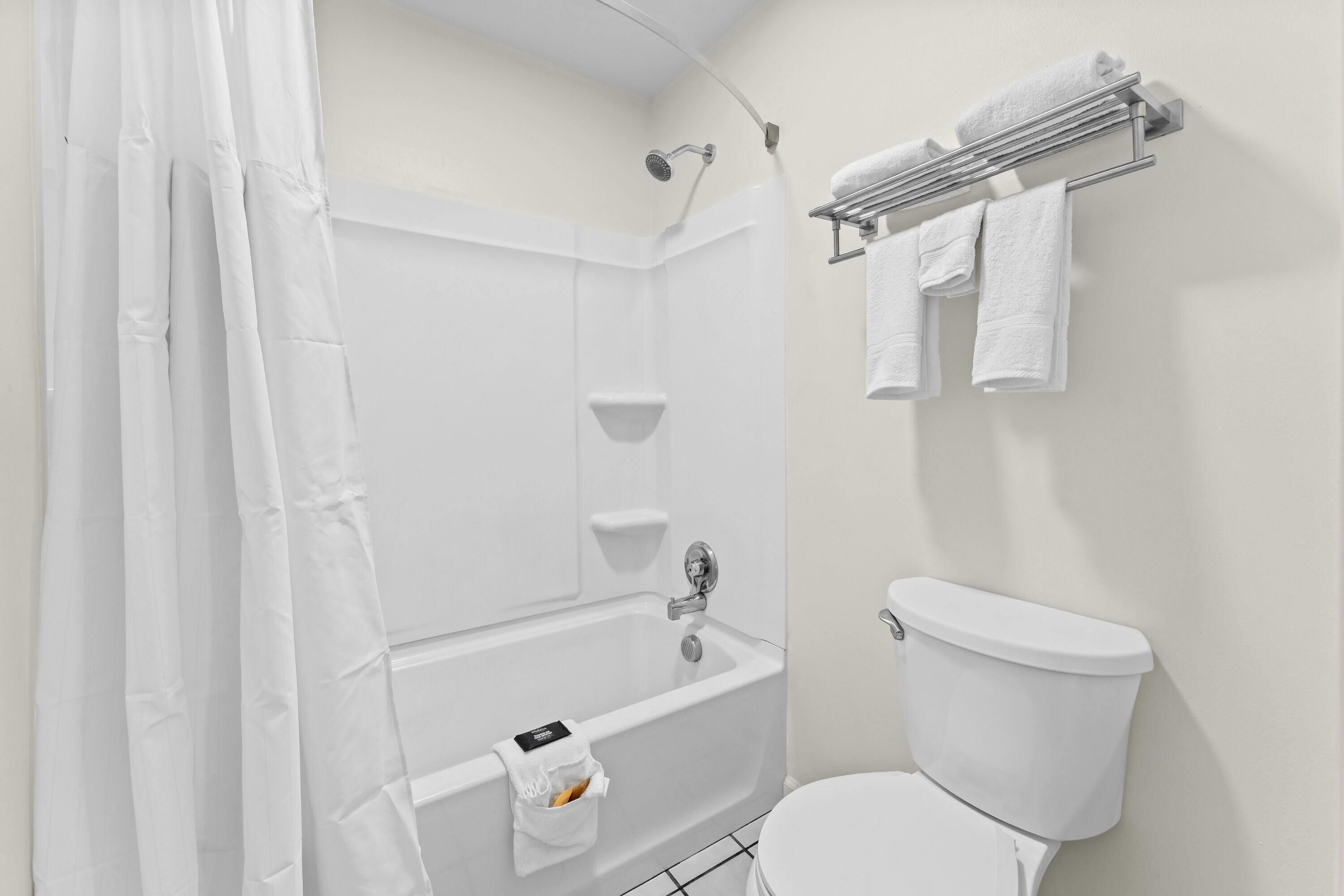 A bathroom with a shower, a toilet, and a towel rack.