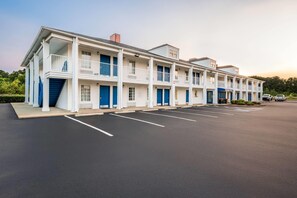 Un motel de varios pisos con una fila de habitaciones, cada una con un balcón y una puerta azul.