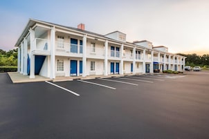 Un motel de varios pisos con una fila de habitaciones, cada una con un balcón y una puerta azul.