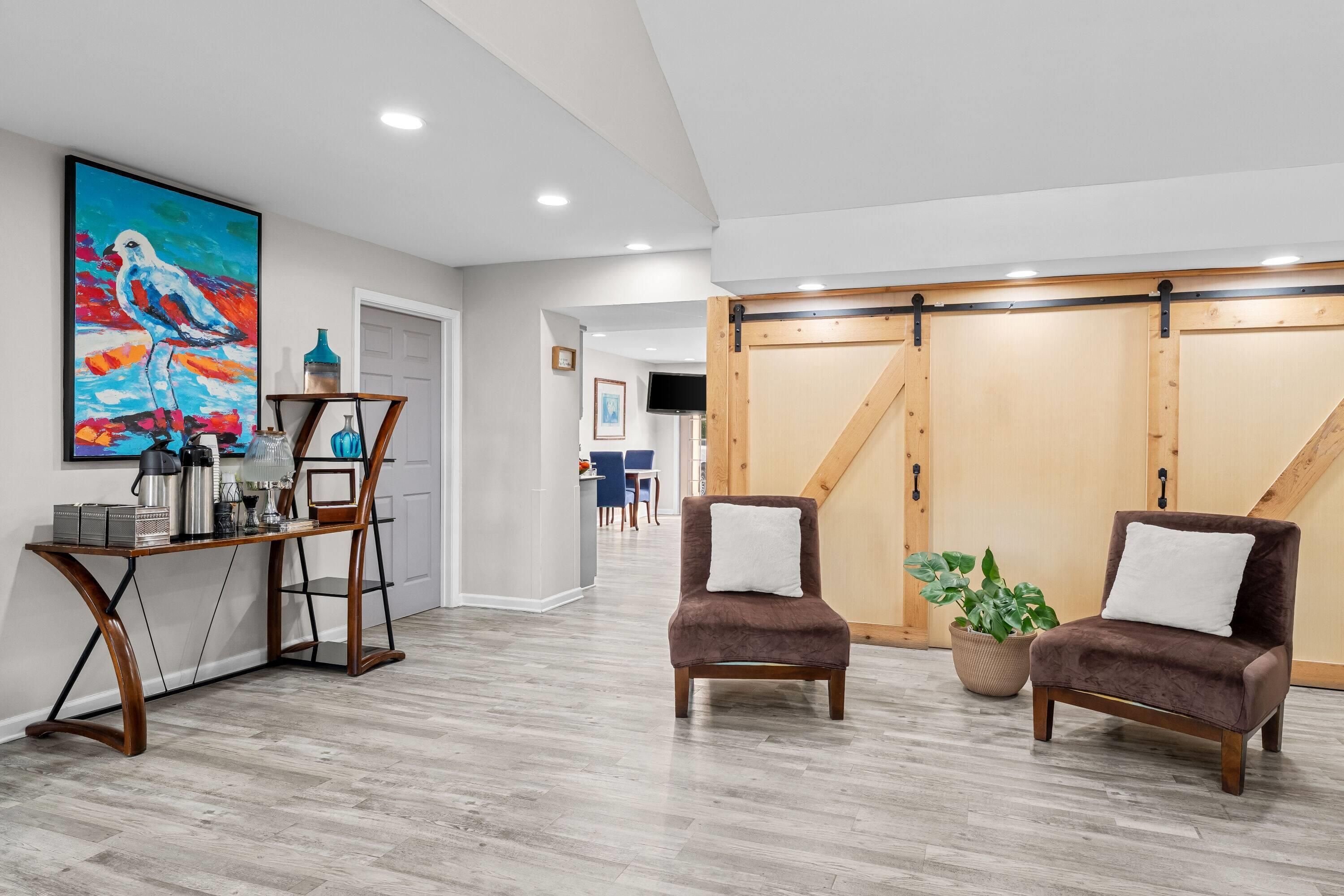 A modern interior with a dining area, two armchairs, a coffee table, and a large painting.