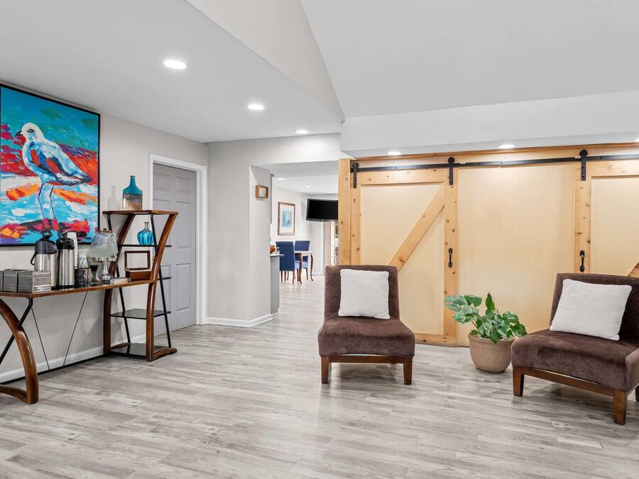A modern interior with a dining area, two armchairs, a coffee table, and a large painting.